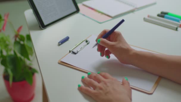 Female hands writing with pen Planes para hoy - Plans For Today in Spanish sign on sheet of paper working with tablet computer sitting at the desk. — 비디오