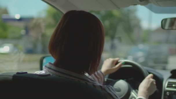 Brunette 30s woman driving car in city. Inside view of female driver holding steering wheel. — Stock Video