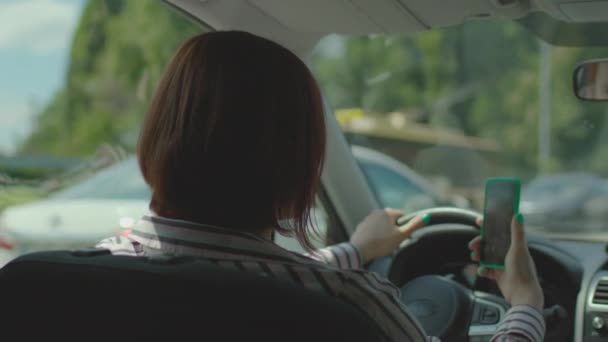 30-as éveiben járó nő autót vezet a városi dugóban és online beszél mobiltelefonos videohívással. Veszélyes vezetőcella a kezében. — Stock videók