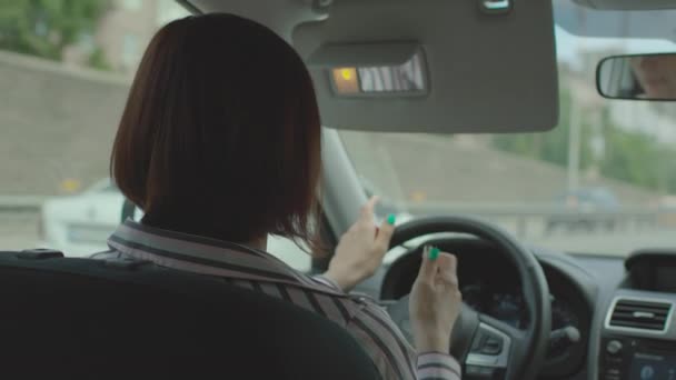 30s female driver applying lipstick driving car in the city. Side view of woman applies make up in the car on the move. — Stock Video