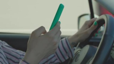 Araba kullanan ve cep telefonu kullanan kadınların ellerini kapatın. Kadın sürücü direksiyon tutuyor ve cep telefonu kullanıyor. Akıllı telefon ellerindeyken tehlikeli sürüş..