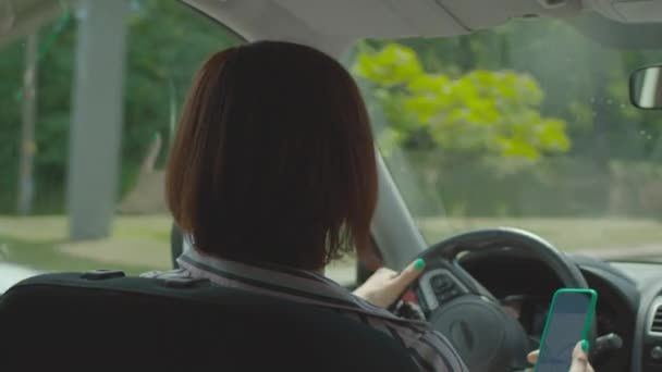 Araba kullanan ve cep telefonunu elinde tutan bir kadın. Direksiyon tutan kadın sürücü ve çevrimiçi harita uygulaması için cep telefonu kullanıyor. Tehlikeli araba sürüşü. — Stok video