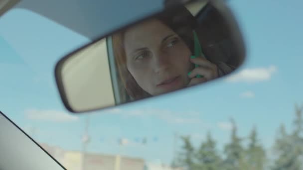 Réflexion miroir de voiture de femme des années 30 conduisant la voiture dans la ville et parlant en utilisant le téléphone mobile. Conduite dangereuse tenant cellule dans les mains. Appel téléphonique de voiture sans équipement mains libres. — Video