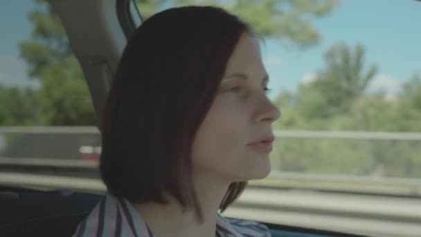 市内で車を運転しながら30代の女性が踊り歌います。マイクとしての携帯電話への女性ドライバーの歌の側面図. — ストック動画