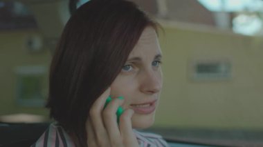 Cep telefonuyla konuşan genç bir kadın el ele tutuşup arabada oturuyor. Kadın sürücü cep telefonuyla konuşuyor..