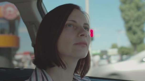 Morena mujer de 30 años conduciendo coche en la ciudad. Vista interior del conductor femenino mirando a su alrededor. — Vídeos de Stock