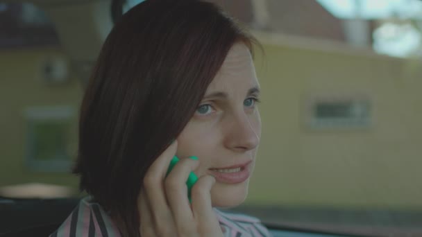 Mujer adulta joven hablando en el teléfono móvil sosteniendo las manos sentadas en el coche. Conductor femenino tiene conversación en el teléfono celular. — Vídeos de Stock