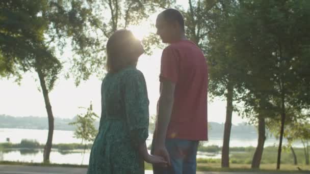 30 років чоловік і жінка цілуються на березі річки на сході сонця. Щаслива пара на вулиці . — стокове відео