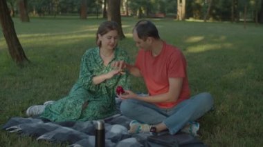 30 'lu yaşlardaki bir adam parkta piknik yaparken sevgili bir kadına evlenme teklif ediyor. Adam gelecekteki karısının parmağına nişan yüzüğü takıyor. Mutlu çift öpüşmesi.