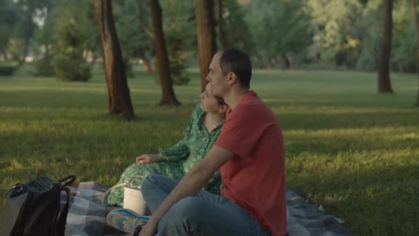 Glada härliga par som har picknick på filt i stadsparken. 30-talet man och hustru njuta av tid tillsammans utanför. — Stockvideo