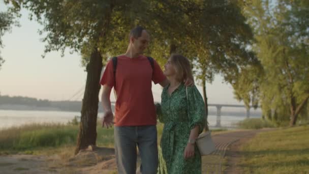Een koppel uit de 30 loopt in het park met rivier bij zonsopgang. gelukkig man en vrouw genieten park lopen samen. — Stockvideo