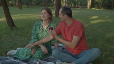 30 'lu yaşlardaki bir adam parkta piknik yaparken sevgili bir kadına evlenme teklif ediyor. Mutlu çift yakında evleniyor. Nişan yüzüğü sunar..