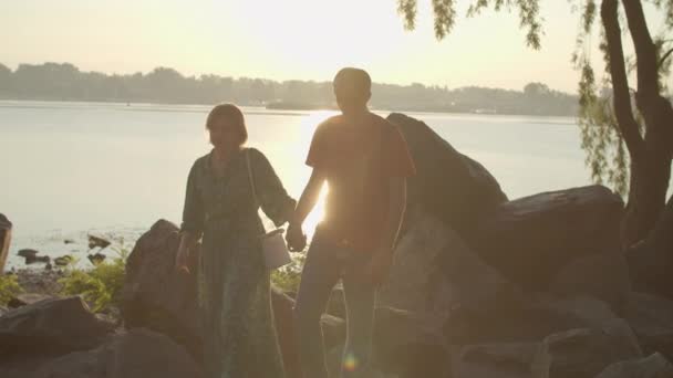 30 ζευγάρια περπατούν δίπλα στο ποτάμι νωρίς το πρωί. Το αγόρι και η φιλενάδα απολαμβάνουν το περπάτημα στο πάρκο. Ευτυχισμένη νεαρή οικογένεια σε εξωτερικούς χώρους την ανατολή. — Αρχείο Βίντεο