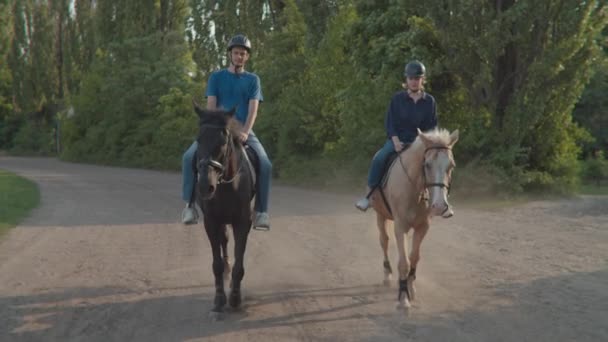 Muž a žena jezdí na koních společně. Pár se učí jezdit na koni. Jezdci na koních a jezdkyně na dostizích. Záběr steadicamu. — Stock video