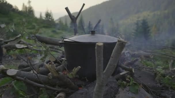 Garnek z wrzącą wodą na ognisku w górach. Kemping gotowanie na zewnątrz. — Wideo stockowe