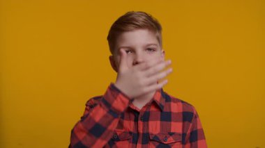 Genç bir çocuk yüzünü klasik bir facepalm jesti ile kapatıyor. Hayal kırıklığını ya da inançsızlığı ifade ediyor. Parlak sarı arka plan onun tepkisini ve duygularını vurguluyor..