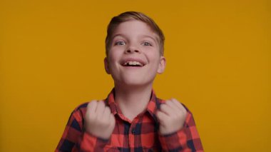 Genç bir çocuk büyük bir gülümsemeyle arkadaşlığını ve heyecanını ifade ederek tokalaşıyor. Parlak sarı arka plan, onun neşeli ve olumlu etkileşimini vurguluyor..