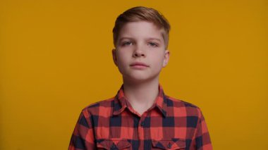 Genç bir çocuk başını arkaya eğiyor, geniş gözlerle bakıyor ve inançsızlık ifadesi sergiliyor. Parlak sarı arka plan onun şaşırmış ve şaşırmış tepkisini arttırır..