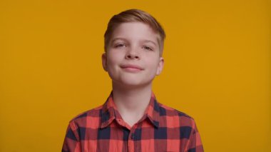 Parlak bir gülümsemesi olan neşeli 10 yaşında beyaz bir çocuk sarı arka plandaki kameraya bakıyor. Neşeli ve pozitif bir portre, çocukluk, mutluluk ve yaşam tarzı içeriği için mükemmel..