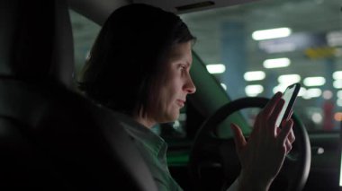 30 'lu yaşlarda bir kadın park halindeki bir arabada otururken Smartphone Navigation App kullanıyor. 4K