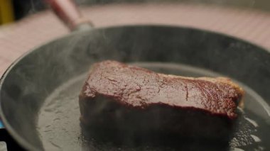 Bifteğin sıcak tavada cızırdadığı yakın plan bir fotoğraf, mükemmelce kızartılmış. Yemek pişirme, aşçılık ve yemek hazırlama içeriği için ideal.