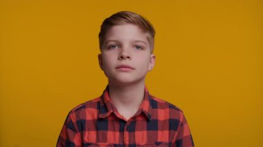 Parlak bir gülümsemesi olan neşeli 10 yaşında beyaz bir çocuk sarı arka plandaki kameraya bakıyor. Neşeli ve pozitif bir portre, çocukluk, mutluluk ve yaşam tarzı içeriği için mükemmel..