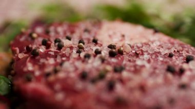 Taze yeşil otlar ve sebzelerle çevrili, tuzlanmış çiğ biftek. Barbekü, aşçılık ve gurme yemek içeriği için mükemmel.