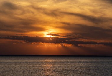 Sarı ve turuncu tanrı ışınlarıyla sersemletici bir gün batımı.