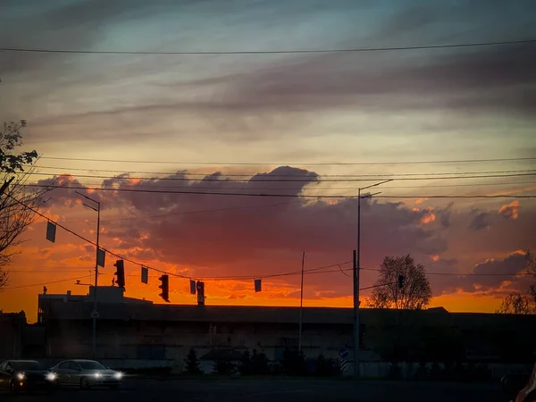 街の車の上に赤とオレンジの空と美しい夕日 — ストック写真