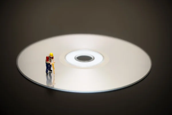 Trabajador en miniatura en la parte superior del disco compacto — Foto de Stock