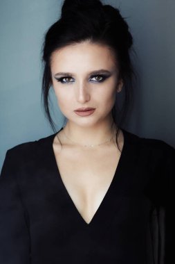 Parlak makyajlı, uzun saçlı, güzel ve güzel bir esmer model. Kozmetik kullanıyor. Göz farı ve rujun canlı renkleri. Salon, makyaj sanatçısı, beyaz model..