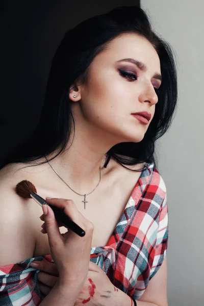 Beautiful young brunette model applying bright make-up