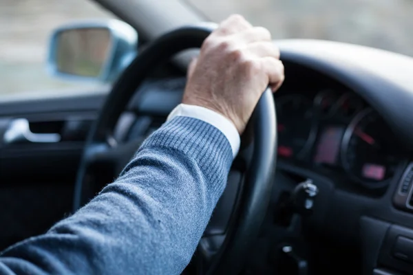 Detal ramienia człowiek trzyma kierownicę w ruchu podczas jazdy. — Zdjęcie stockowe
