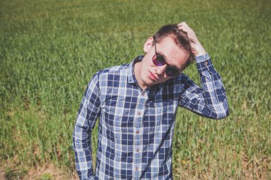 Güneş gözlüklü sarışın adam. Yeşil doğa arka plan.