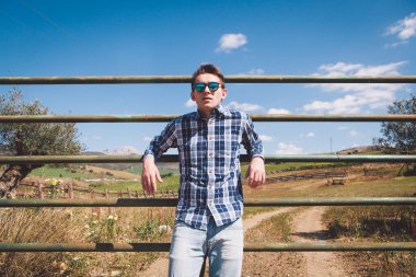 Genç adam bir kırsal çiftlik çitte poz.