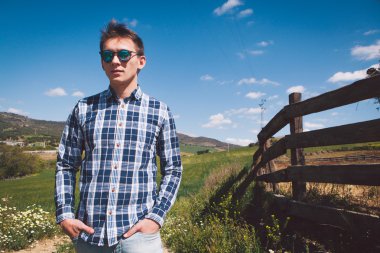 Genç adam bir tarım arazisi poz güneş gözlüğü.