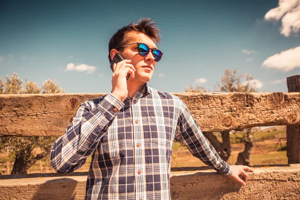 Νεαρός άνδρας μιλώντας από τηλεφώνου στην ύπαιθρο. — Φωτογραφία Αρχείου