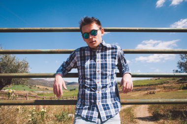 Genç adam bir tarım arazisi poz güneş gözlüğü.