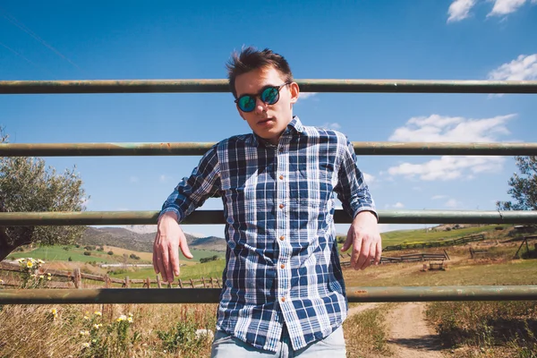 Genç adam bir tarım arazisi poz güneş gözlüğü.