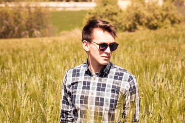 Genç sarışın adam portre bir sivri çayırda.