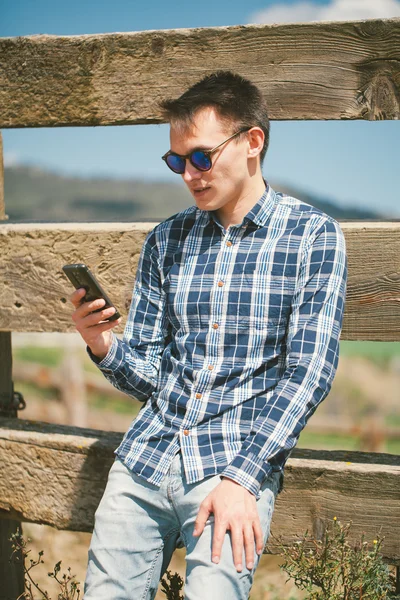 Tarım arazisi, elinde bir akıllı telefon ile genç adam. — Stok fotoğraf