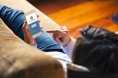 Evde yalan süre WordPress app bir akıllı telefon kullanan kadın.