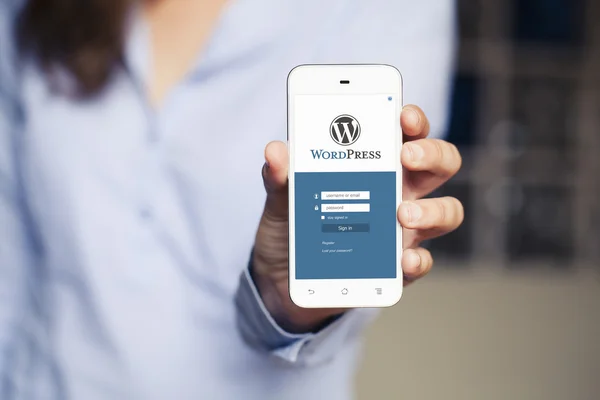 Kadın el bir cep telefonu ile Wordpress app içinde belgili tanımlık perde tutarak.