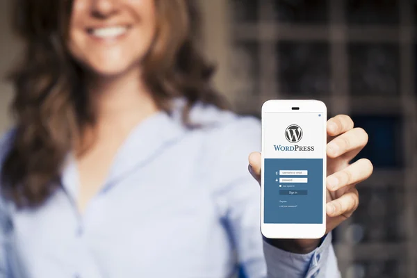 WordPress ιστοσελίδα σελίδα σύνδεσης σε μια οθόνη κινητού τηλεφώνου. Γυναίκα, κρατώντας το. — Φωτογραφία Αρχείου