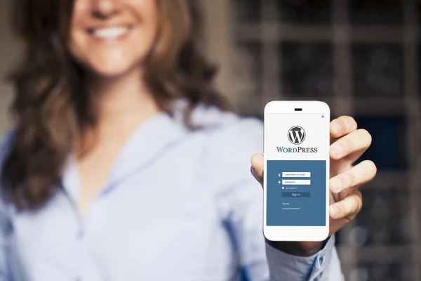 Wordpress página do site de login em uma tela de telefone móvel. Mulher segurando . — Fotografia de Stock
