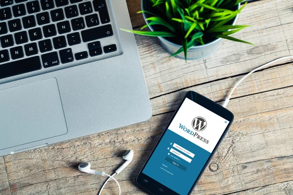 WordPress app на екран мобільного телефону. Вид зверху дерев'яні на робочому місці. — стокове фото