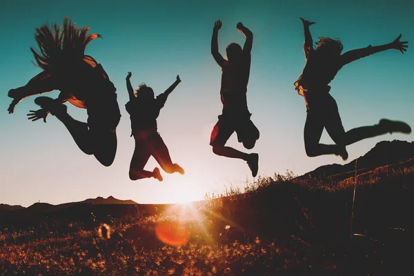 Amigos saltando sobre el cielo al atardecer — Foto de Stock