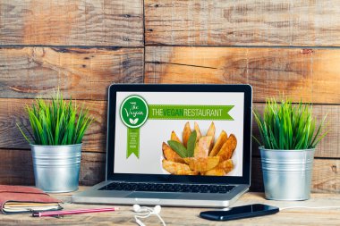 Vegan Restoran bir dizüstü bilgisayar Web sitesi. Ahşap çalışma alanı.
