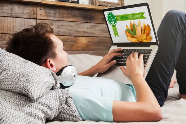 Homme visitant un site de restaurant végétalien, couché à la maison . — Photo