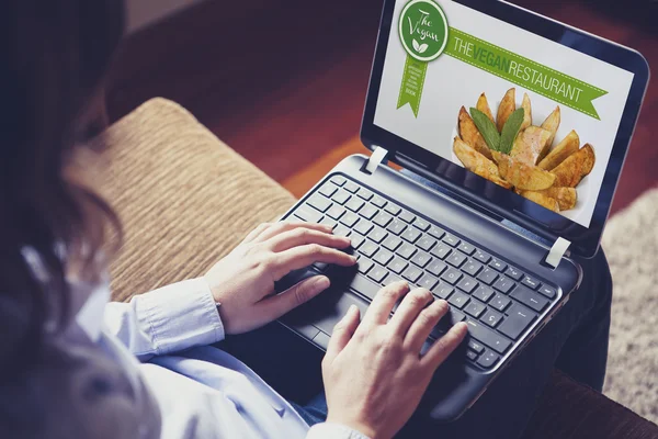 Mujer visitando un sitio web restaurante vegano con un ordenador portátil en casa . — Foto de Stock